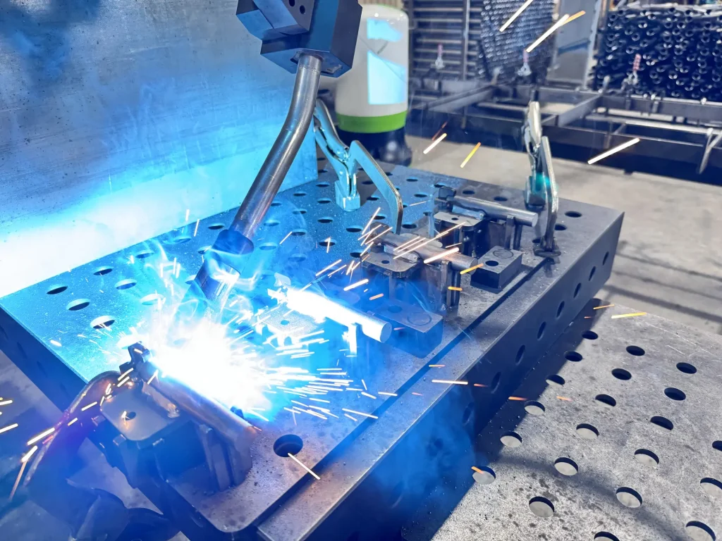 Robotic welder throwing sparks in the Stein-Way fabrication shop